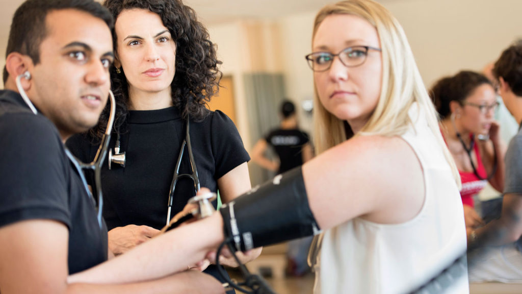 Dr. Jennifer Rockfeld, assistant professor of medical sciences at the Frank H. Netter MD School of Medicine at Quinnipiac University, observes first-year medical students Naveen Reddy, left, and Britton Gibson taking vital signs. Photo by Autumn Driscoll of Quinnipiac University.